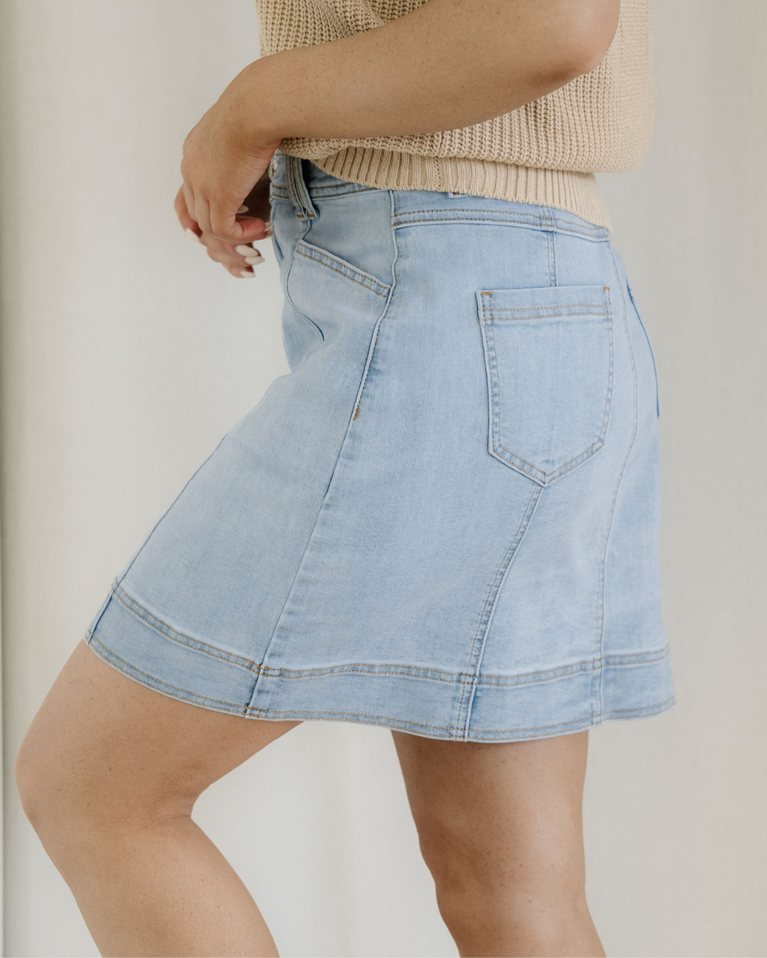 Light blue denim skirt worn by a person on a plain background