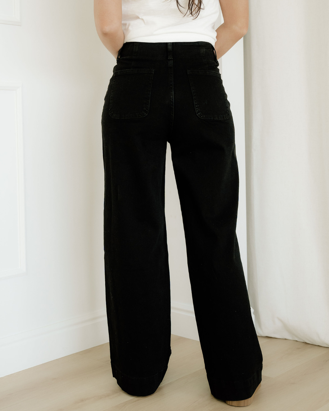 Person wearing black wide-leg pants and a white top against a white background