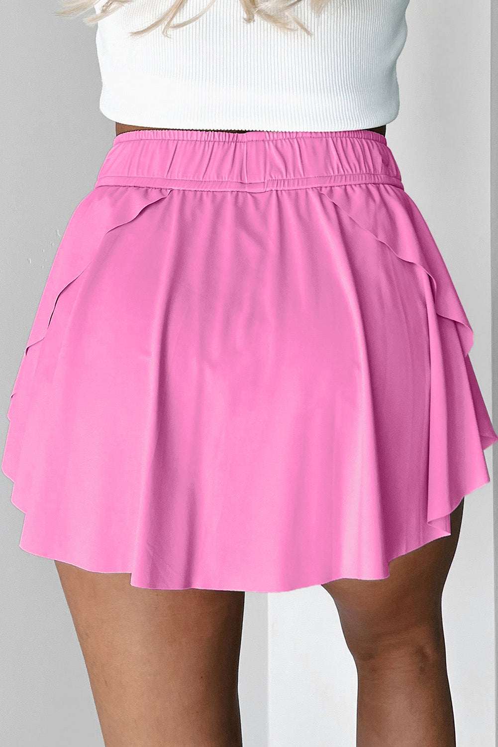 Back view of a pink fabric tennis skort with an elastic waistband and layered ruffle hem.