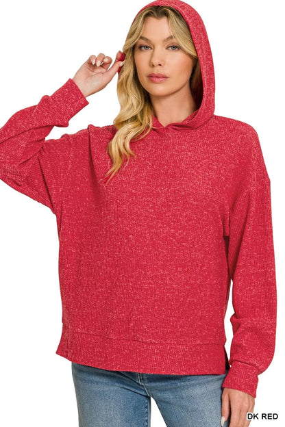 A woman wearing a heathered red pullover hoodie with blue jeans, shown against a plain white background. She is holding up one of her fingers, and a text label 'DK RED' is visible in the bottom right corner.