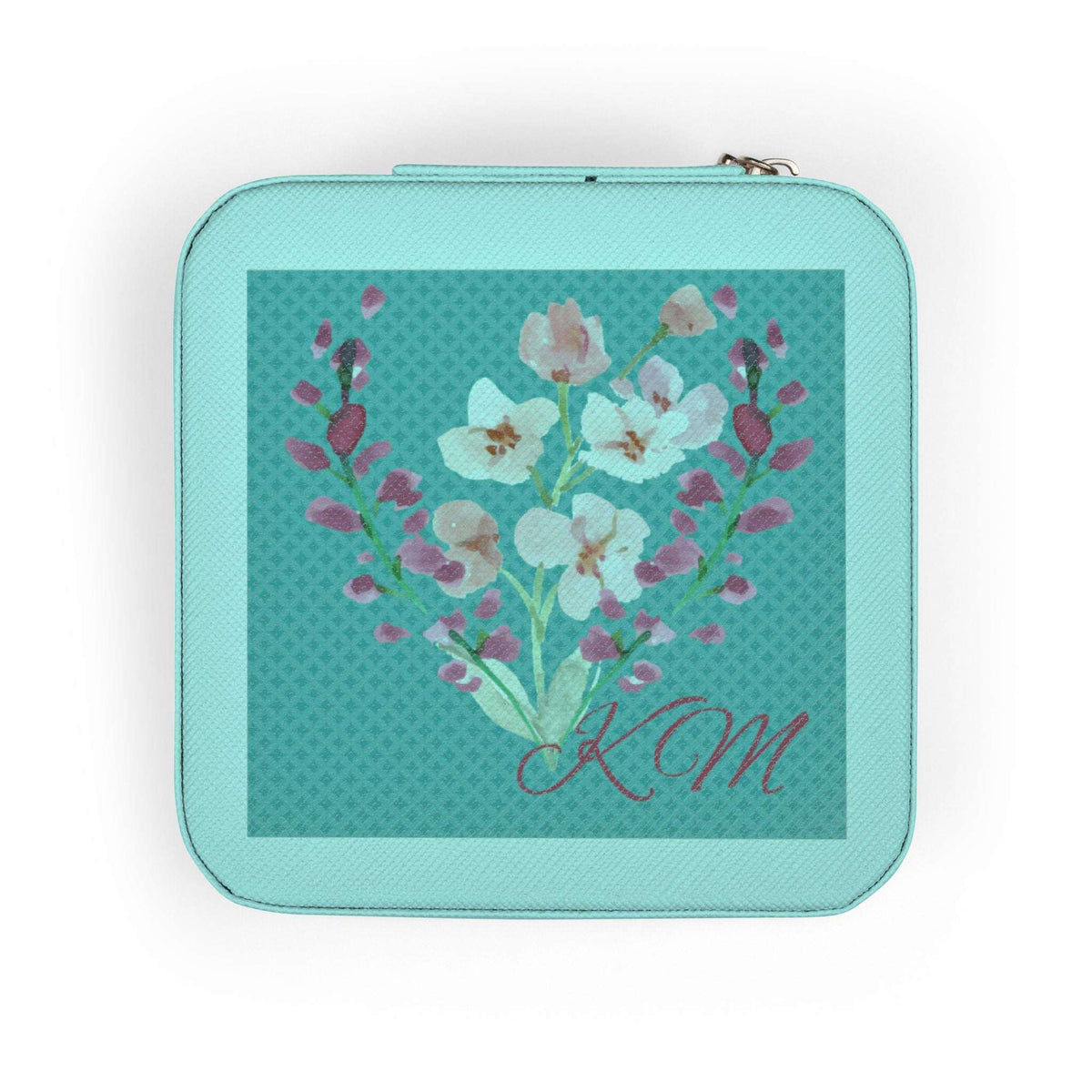 A square zippered pouch in mint green with a central floral print featuring white and pink blossoms on a teal patterned background, with the initials 'KM' in cursive at the bottom.