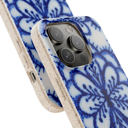 A close-up of a smartphone case with a blue floral or lace-like pattern on a white base and a speckled beige edge, shown fitted on a phone against a clean white background.