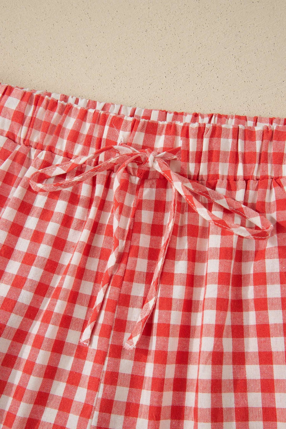 Red and white gingham fabric shorts with an elastic waistband and matching fabric tie bow.