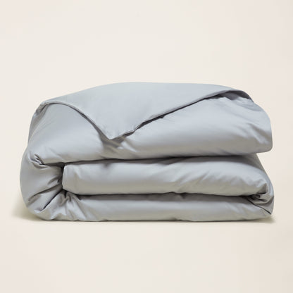 Folded light blue comforter on a beige background