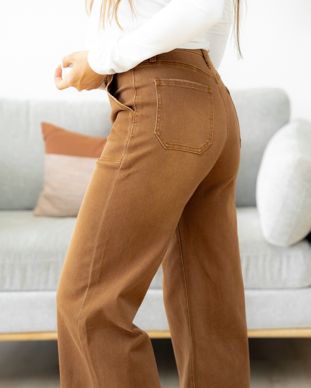 Person wearing brown wide leg cropped jeans. Close up view.