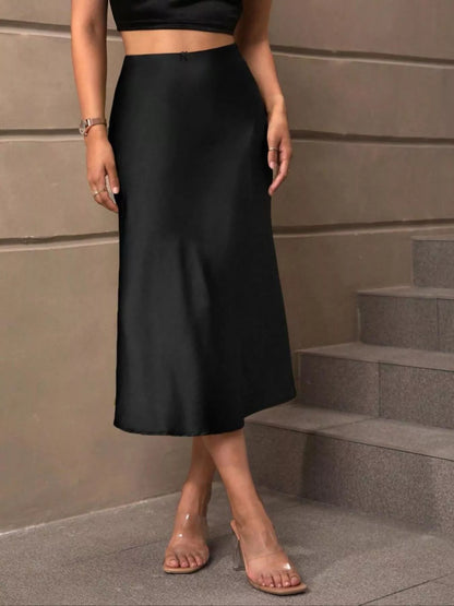 Person wearing a black skirt standing on steps against a beige wall