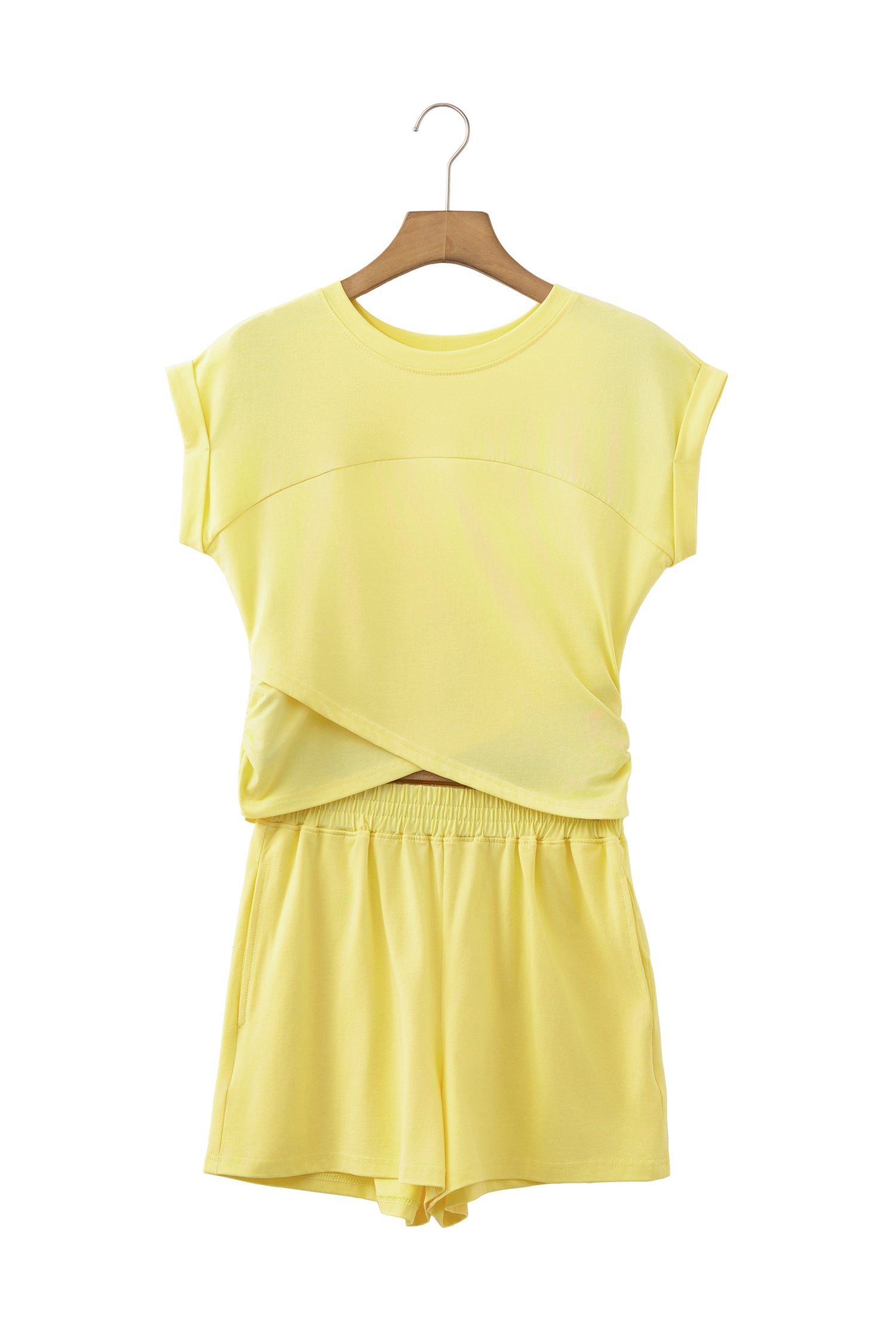 A two-piece women's lounge set in pale yellow, featuring a short-sleeve crewneck top with a crossover front detail and matching shorts, displayed on a wooden hanger against a white background.