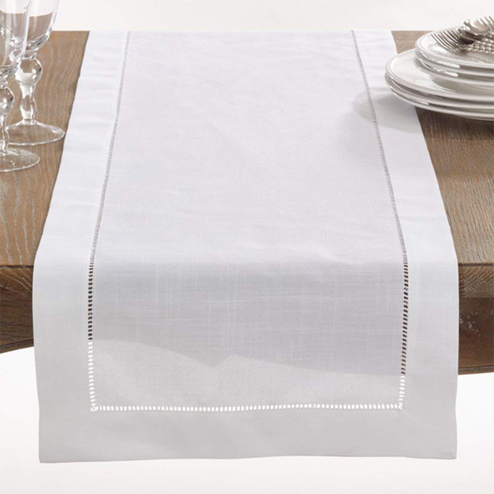 White table runner on a wooden table with plates and glasses.