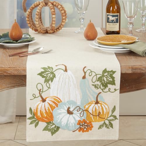 Table setting with a decorative table runner featuring pumpkins and leaves on a wooden table.