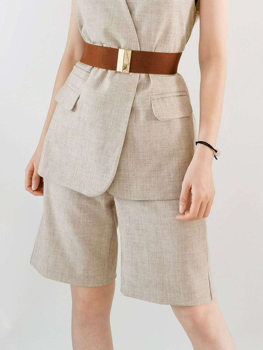 Person wearing a beige suit with a brown belt on a plain background