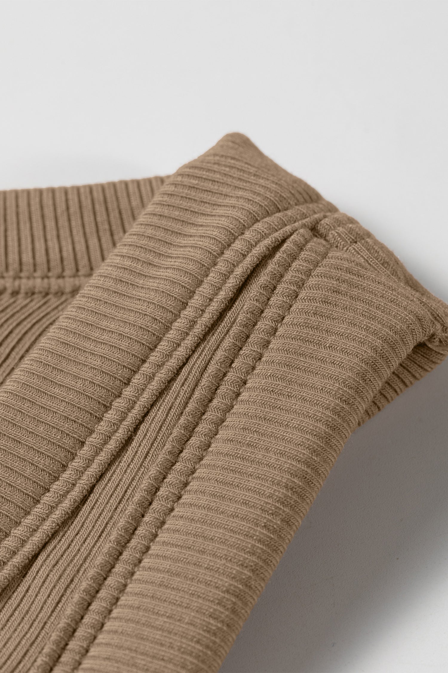 Close-up of a folded brown ribbed fabric tank top showing the textured vertical lines and shoulder seam.