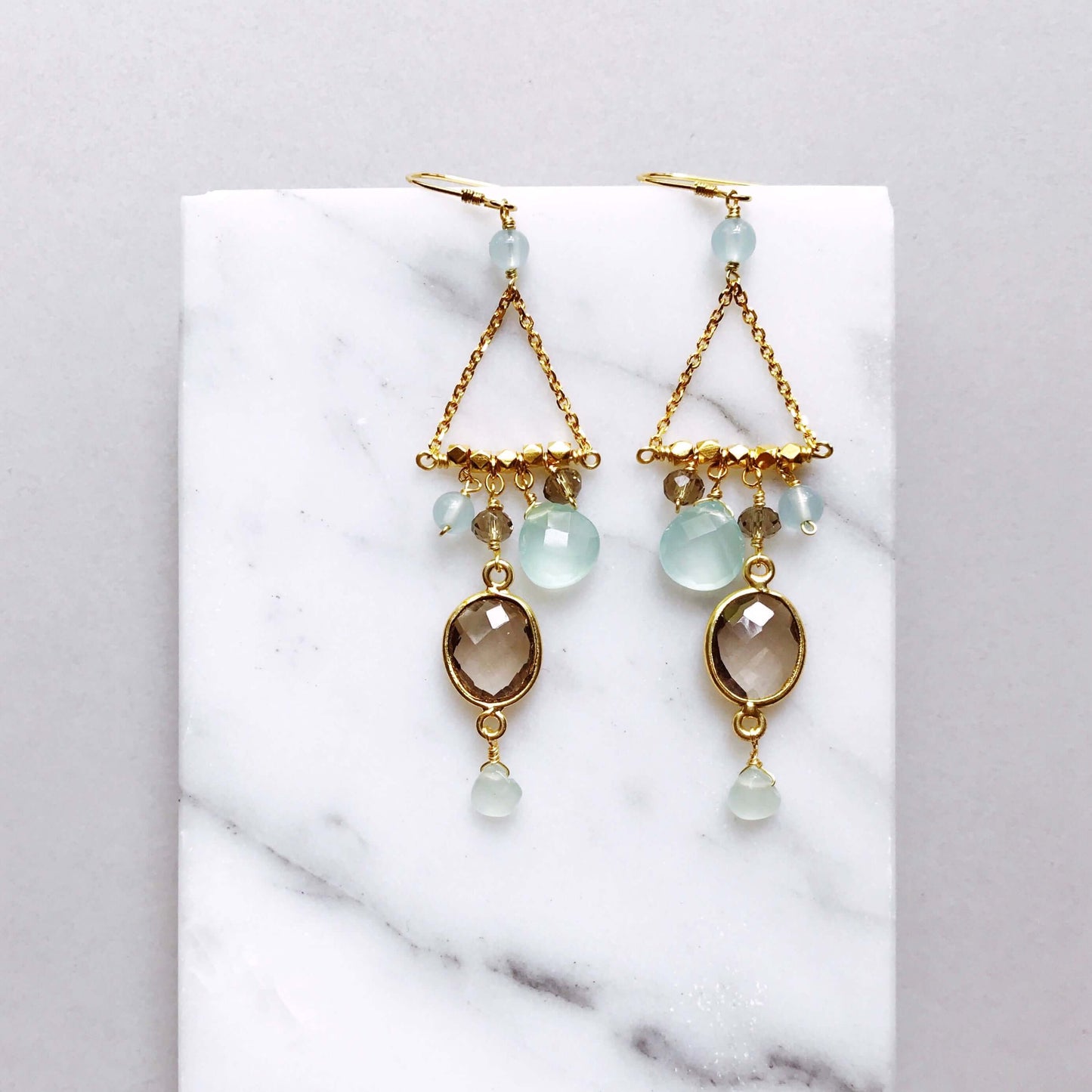 Gold earrings with gemstones on a marble surface