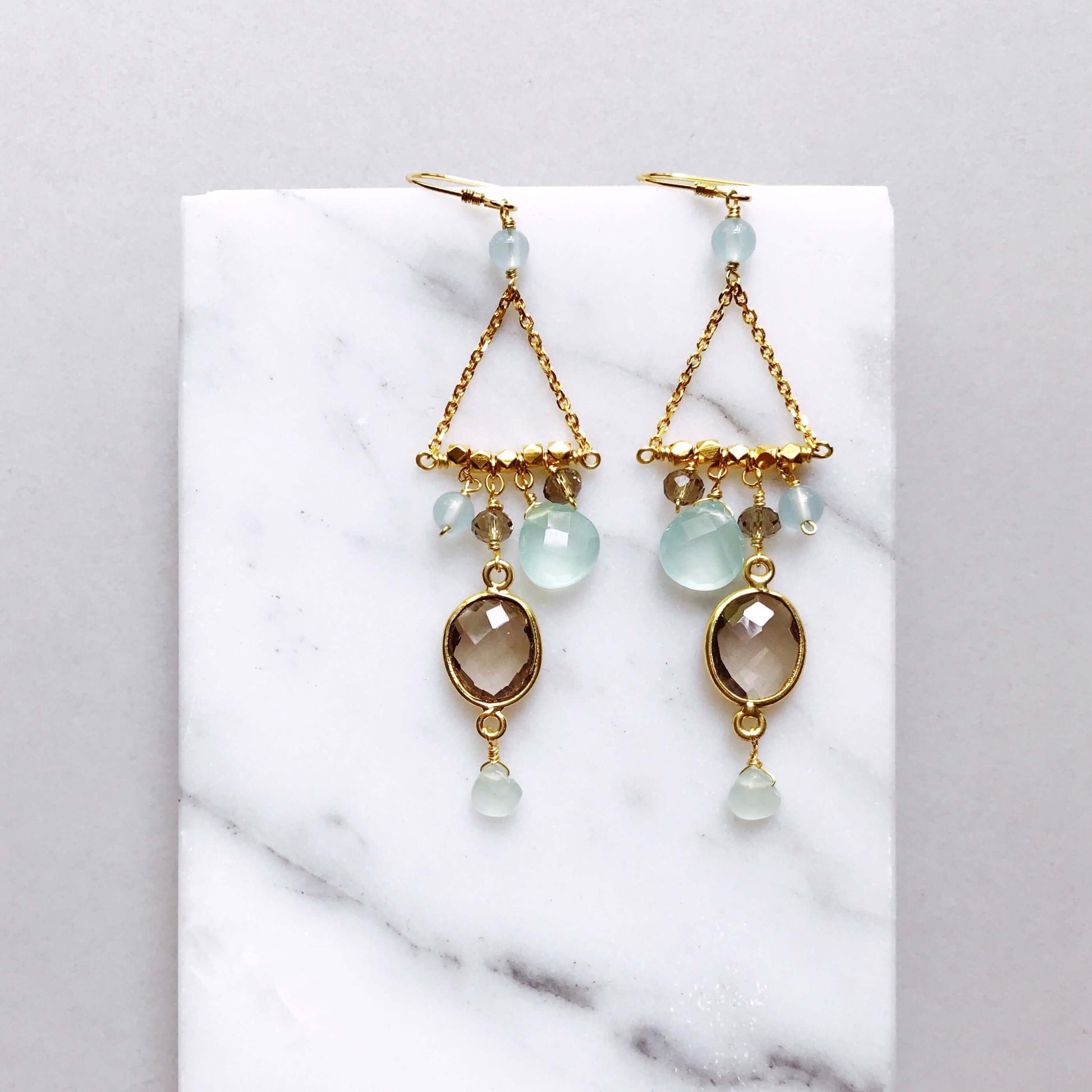 Gold earrings with gemstones on a marble surface