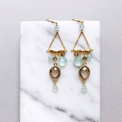 Gold earrings with gemstones on a marble surface