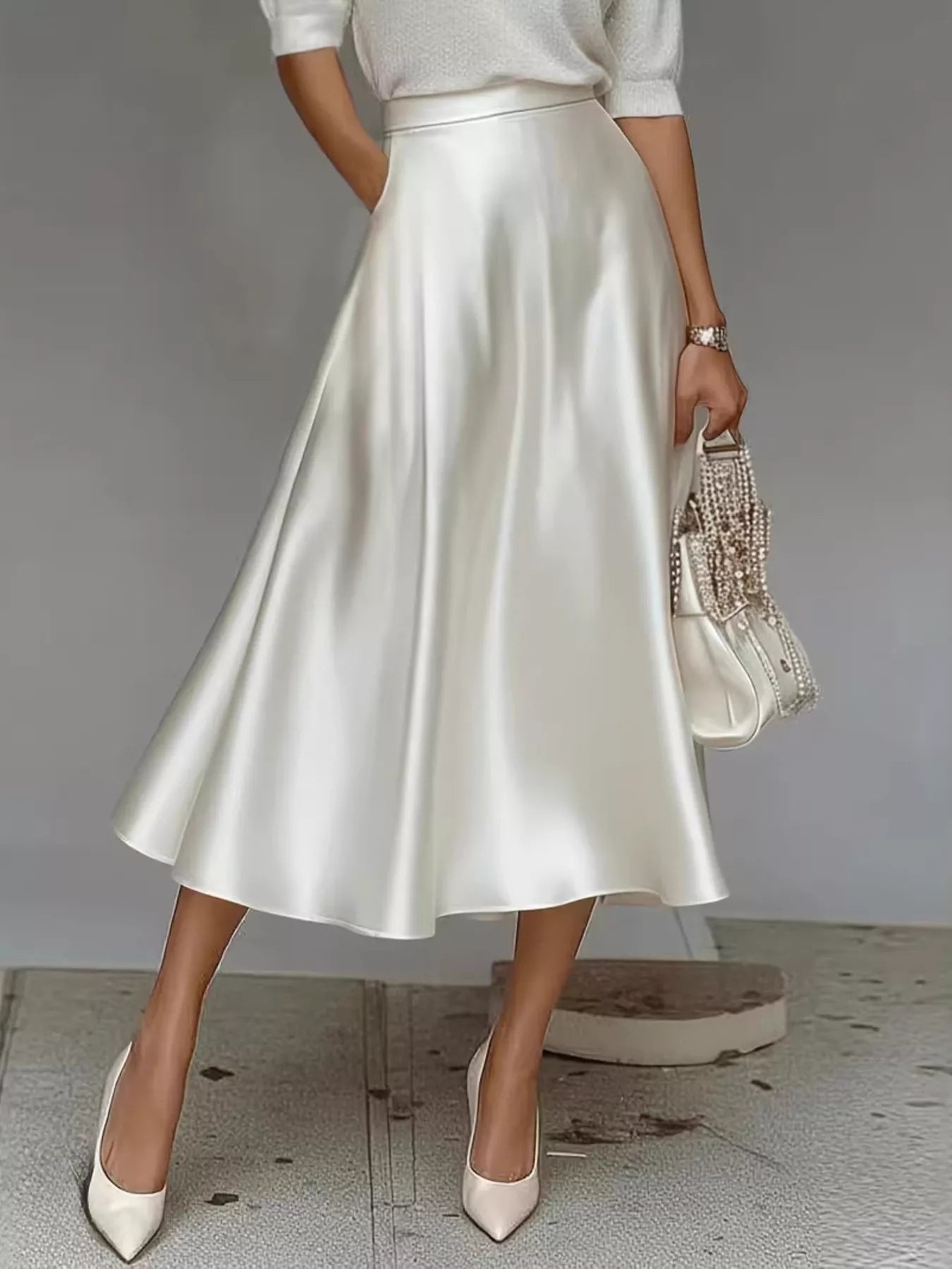 Person wearing a white satin skirt with a plain background