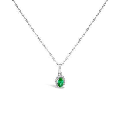10K white gold pendant necklace featuring a 5x3mm green emerald surrounded by diamond accents on an 18" chain.