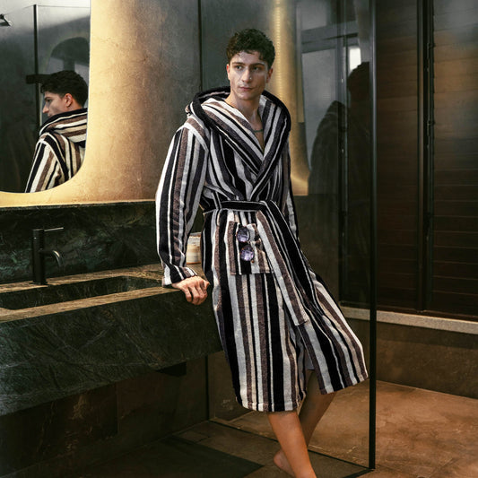 Person wearing a black and white striped robe in a bathroom.