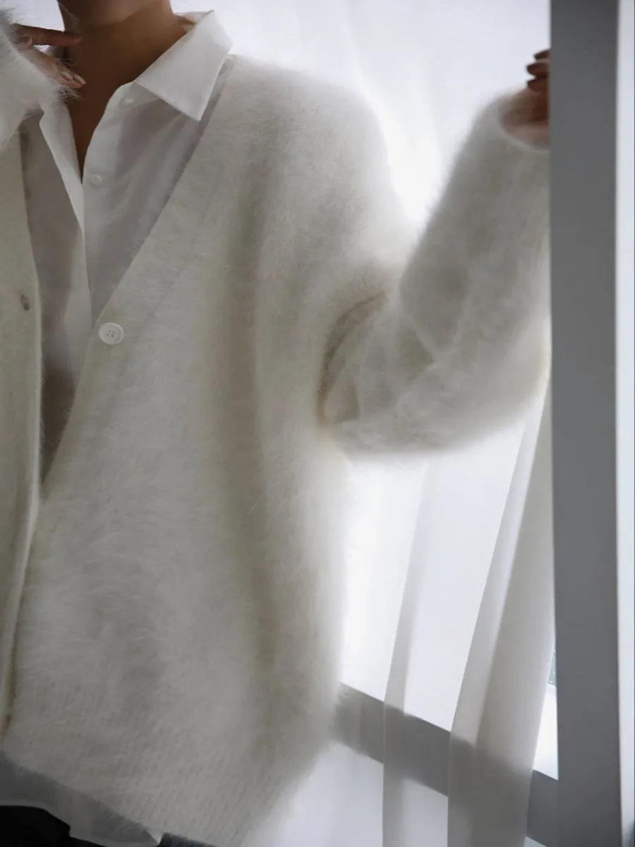 Person wearing a white shirt and light gray sweater against a white background