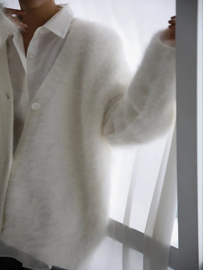 Person wearing a white shirt and light gray sweater against a white background