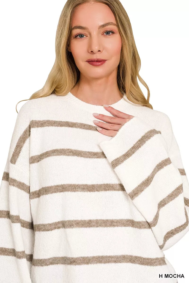 A woman wearing a fuzzy knit sweater with horizontal taupe-brown stripes on an off-white background, shown against a plain white studio backdrop.