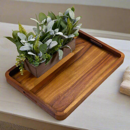 Wooden tray with a wooden planter and greenery on a light surface.