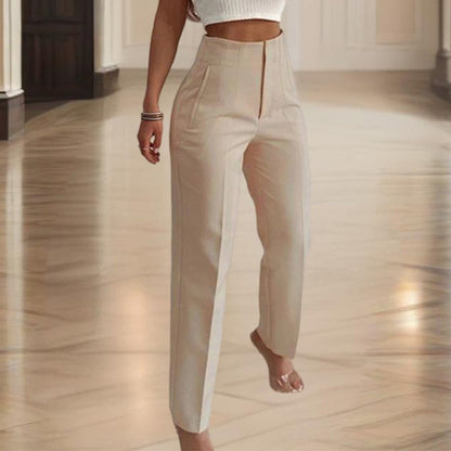 Person wearing beige high-waisted pants in a room with wooden flooring.