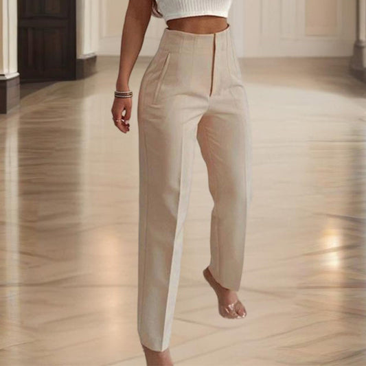 Person wearing beige high-waisted pants in a room with wooden flooring.