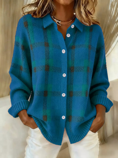 Person wearing a blue plaid cardigan with white pants indoors.