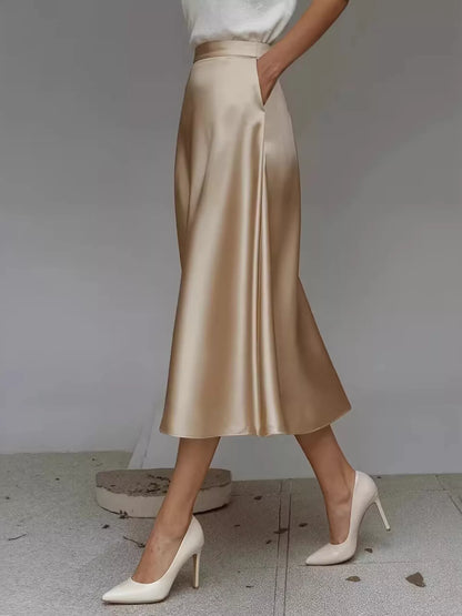 Gold satin skirt worn by a person on a neutral background