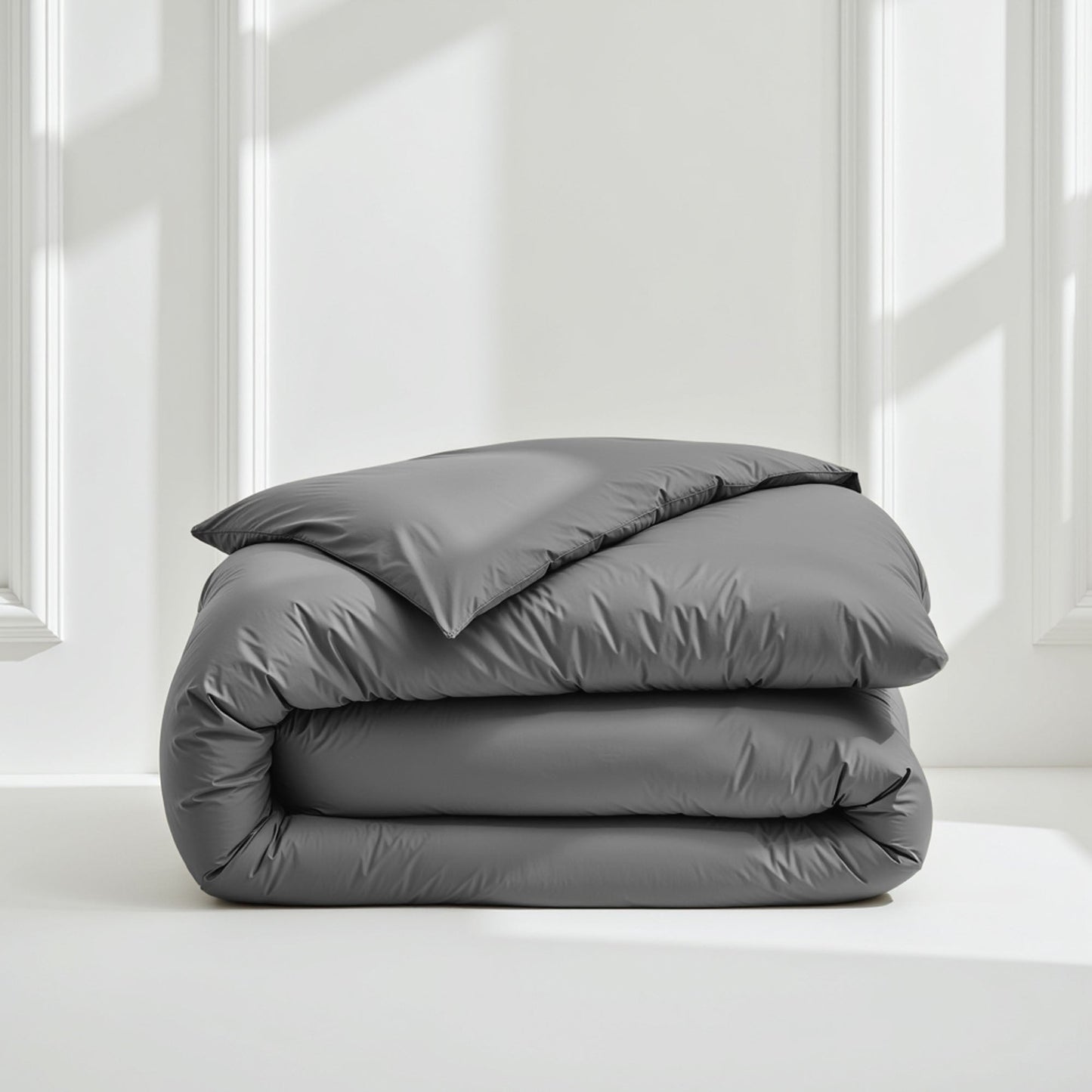 Folded gray comforter on a white surface with a light gray wall background
