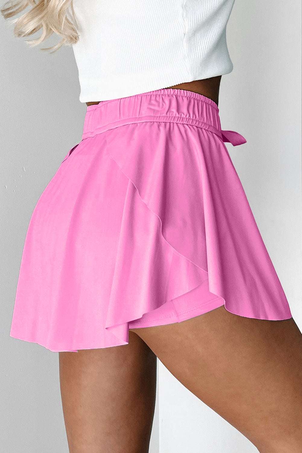 Pink fabric tennis skort with an elastic drawstring waistband and built-in liner shorts.