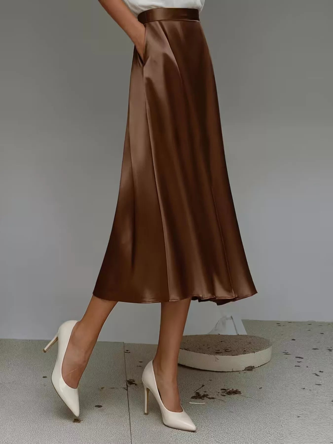 Brown satin skirt worn by a person on a plain background