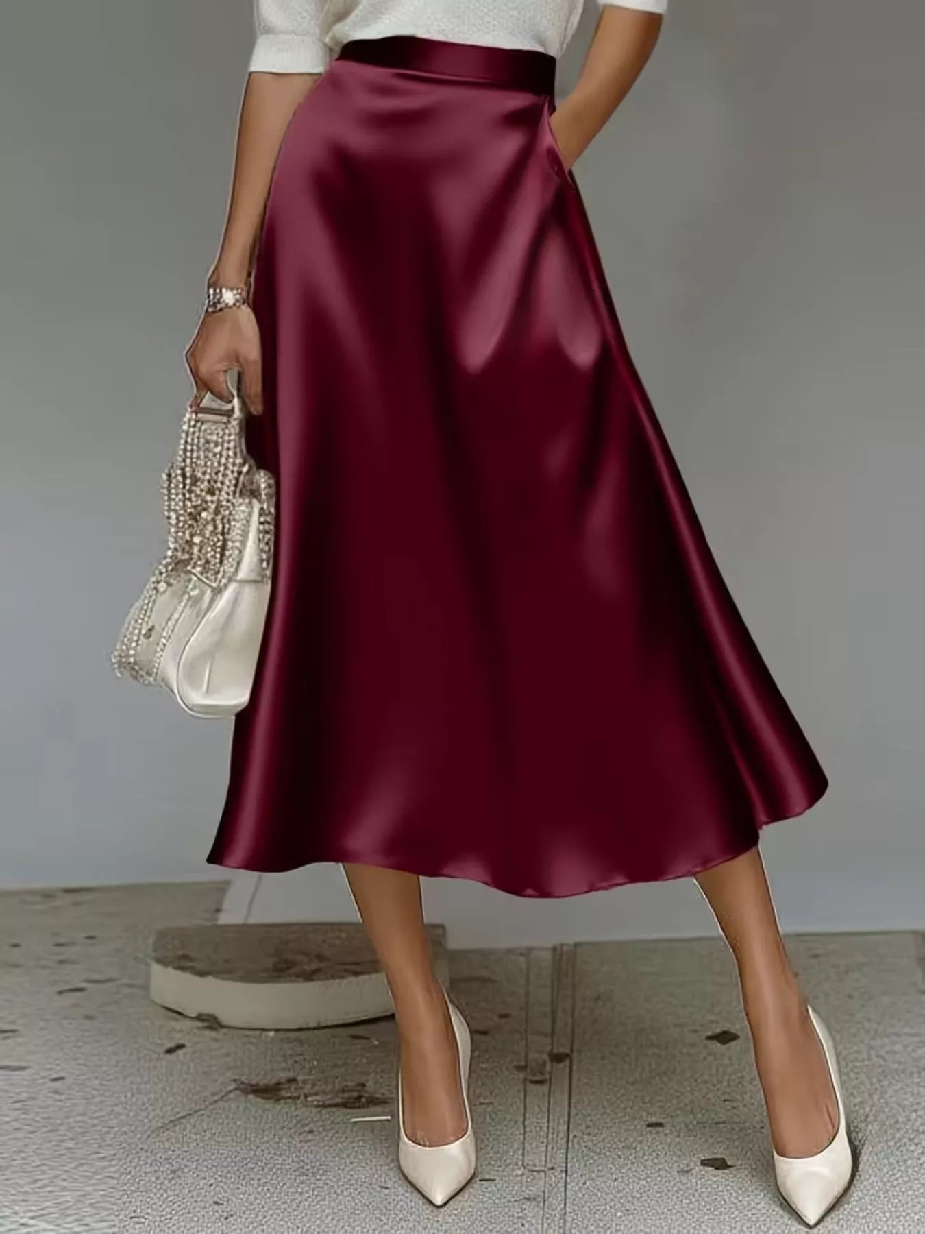 Person wearing a burgundy satin skirt with a plain background