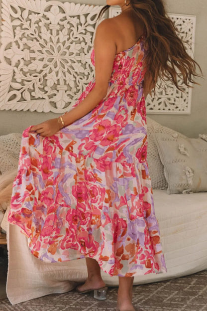 Woman wearing a colorful floral dress sitting on a couch.