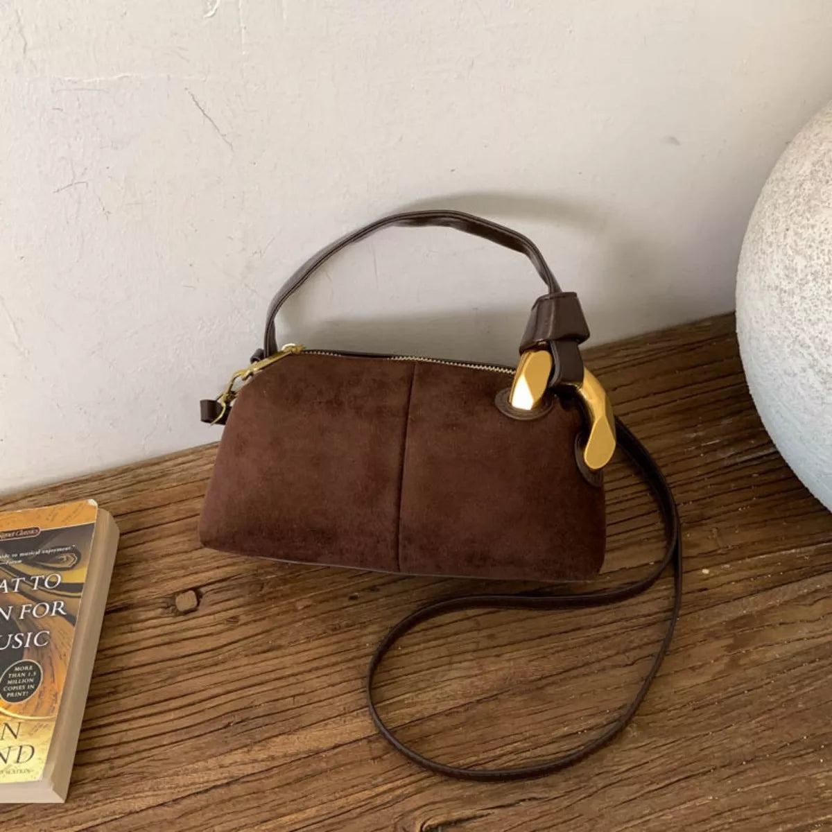 Brown handbag on a wooden surface with a white wall background