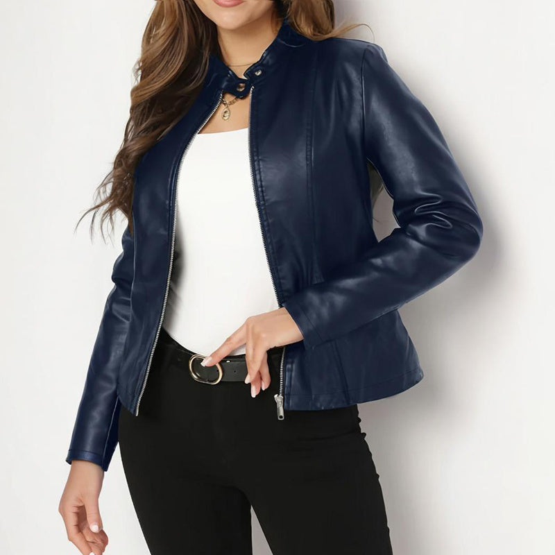 Person wearing a blue leather jacket over a white top and black pants on a light background