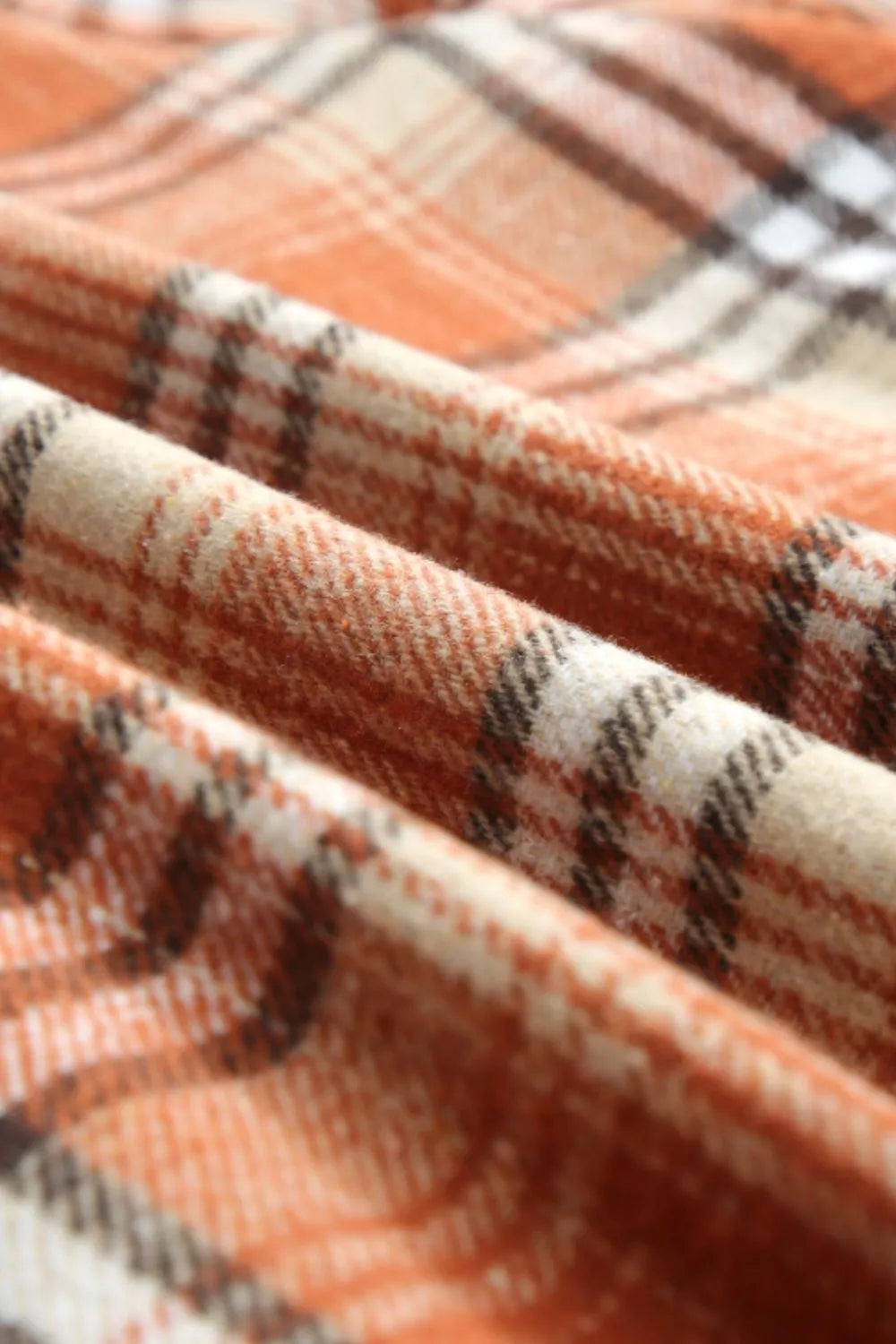 Close-up of plaid fabric with orange, beige, and black pattern