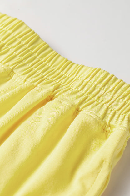 Close-up of a bright yellow garment with an elasticized gathered waistband, photographed against a plain light background.