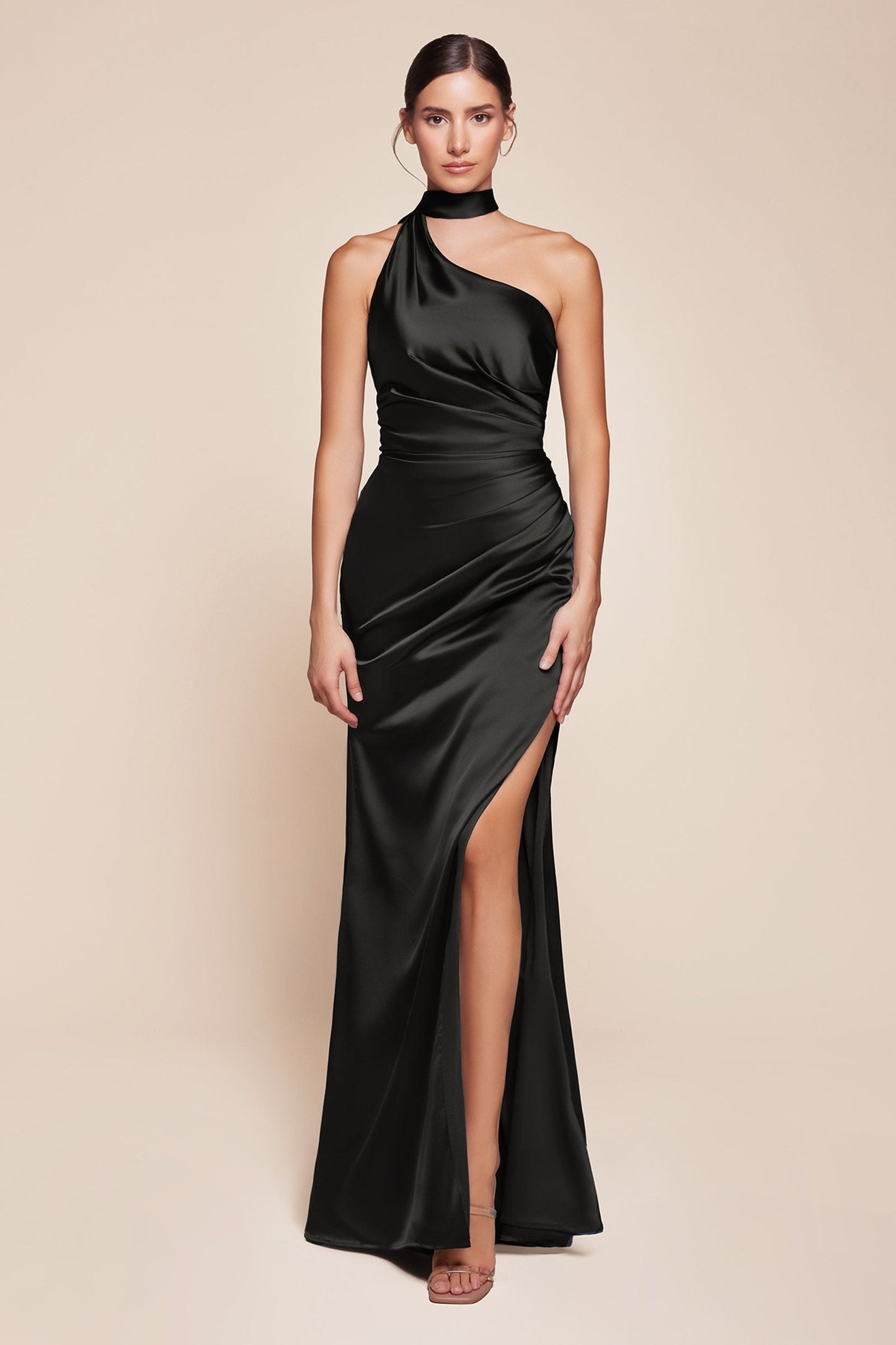 Woman wearing a black halter neck gown with a high slit on a beige background