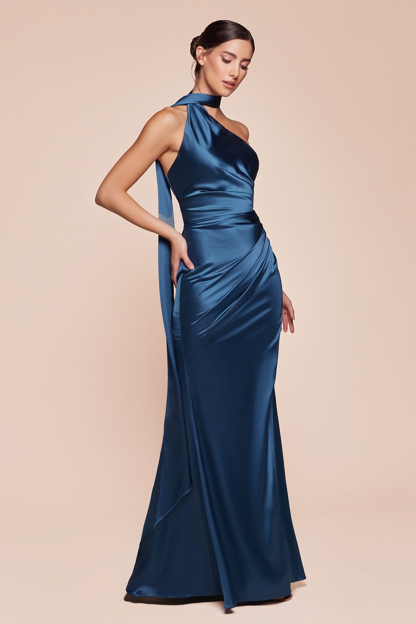 Woman wearing a blue satin evening gown on a beige background