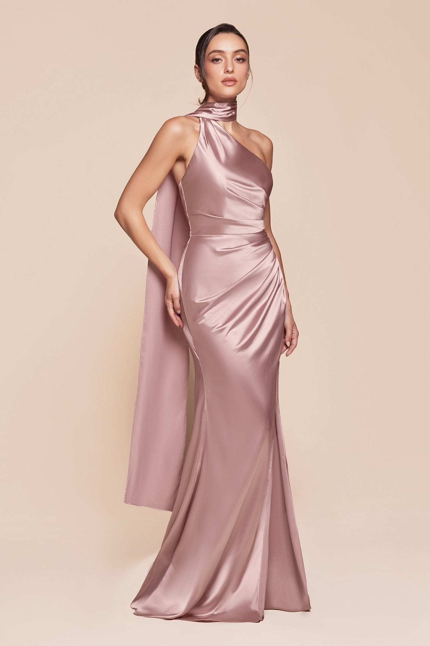 Woman wearing a pink satin halter neck gown on a beige background