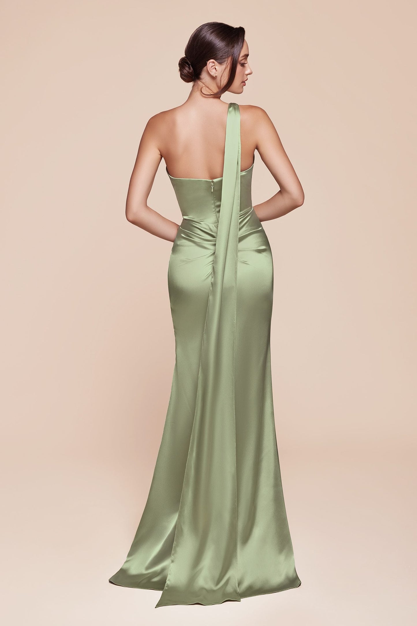 Woman wearing a green evening gown with a sheer back on a beige background