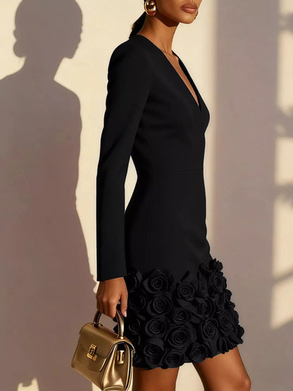 Woman wearing a black dress with floral details, holding a gold handbag against a neutral background