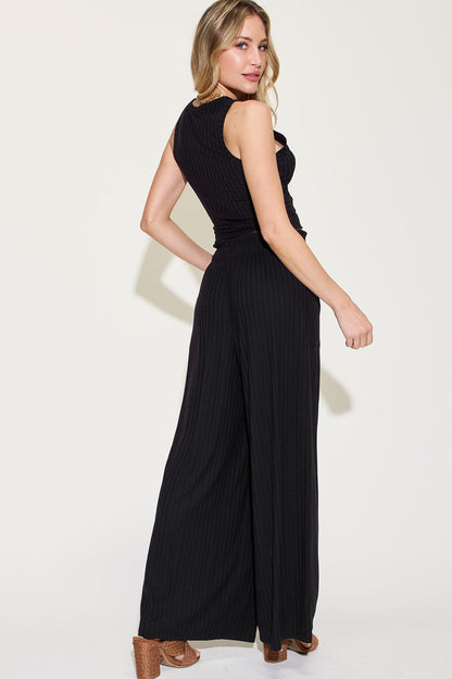 Black ribbed tank top paired with wide-leg pants, model facing away, showcasing the back view and side profile.