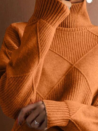 A close-up of a person wearing a chunky knit turtleneck sweater in a warm burnt orange color, featuring diamond-shaped cable knit patterns and ribbed cuffs.