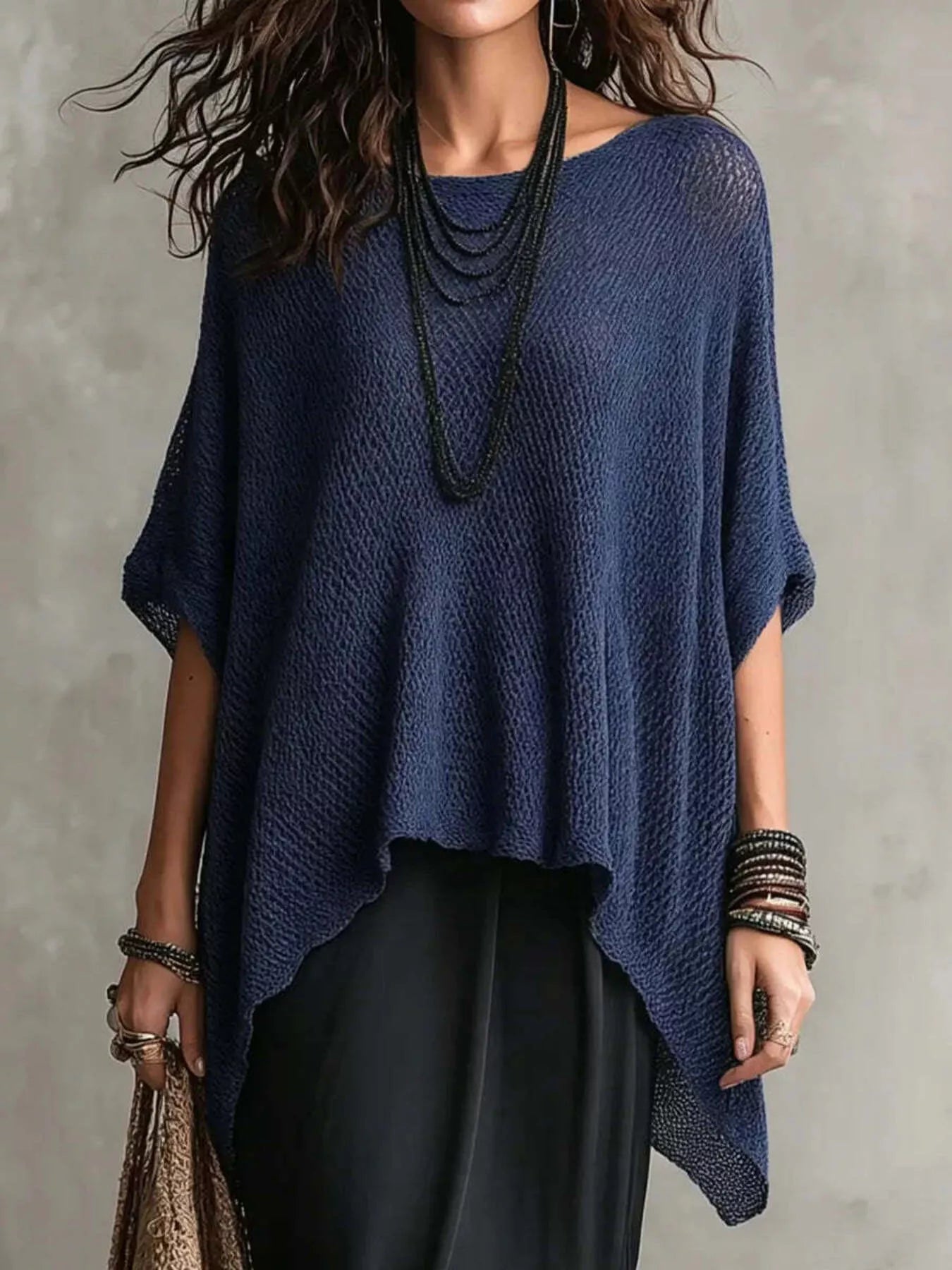 Woman wearing a blue knitted poncho against a gray background