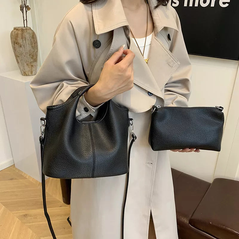 Person holding two black handbags indoors