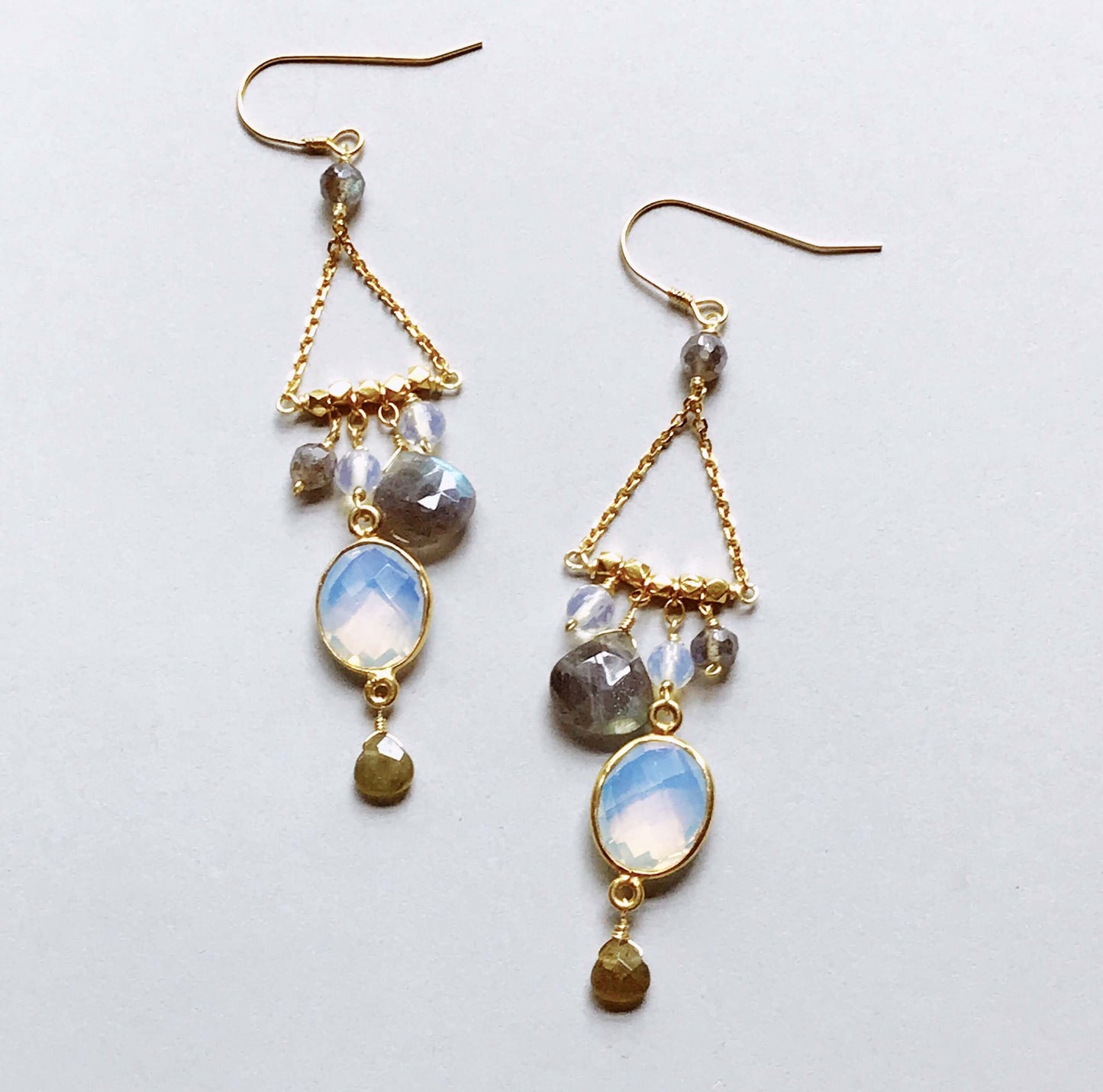 Gold earrings with gemstones on a light gray background