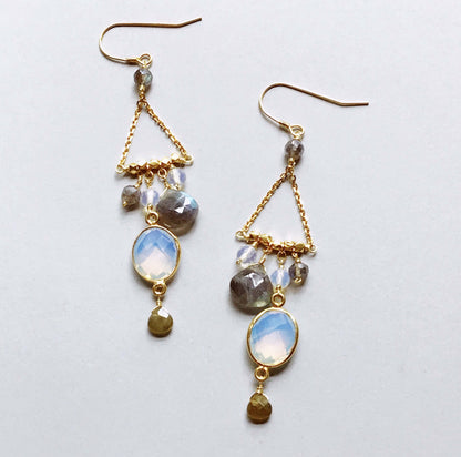Gold earrings with gemstones on a light gray background