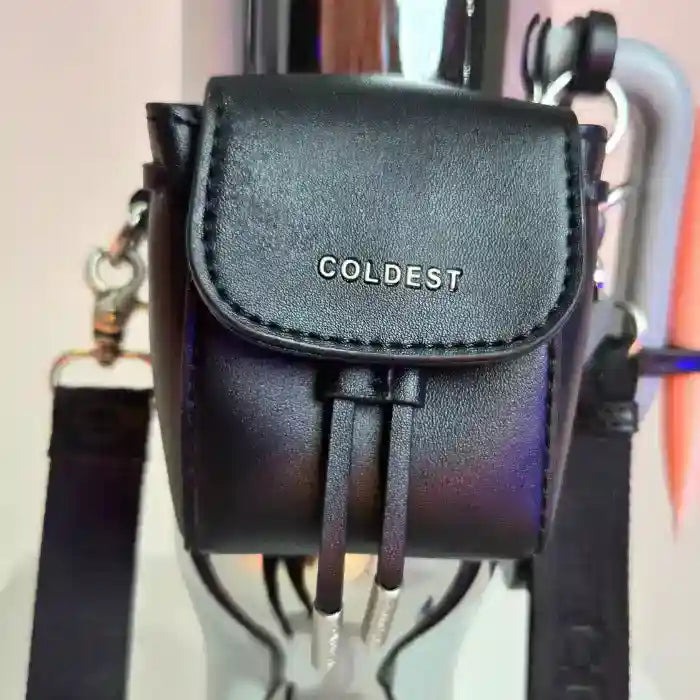 Black mini backpack with a clasp, featuring the word "COLDEST" embossed on the front, attached to a water bottle.